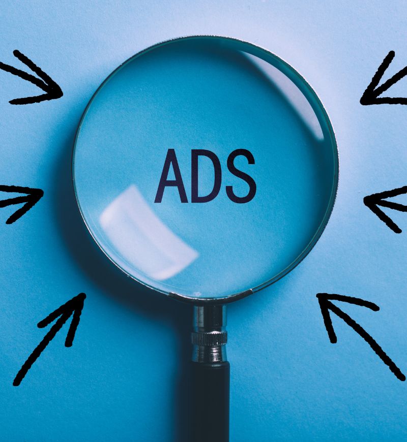 Loupe sur le mot “ADS” au centre, entouré de flèches noires pointant dans différentes directions sur fond bleu. Intègre le concept seo définition de manière fluide.